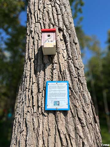A South Hero birdhouse up close — red roof, round entry hole, and the informational sign posted below. Photo: Erma via Roadside America