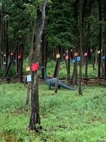A dinosaur keeps watch over the birdhouse forest. Photo: Tracy via Roadside America