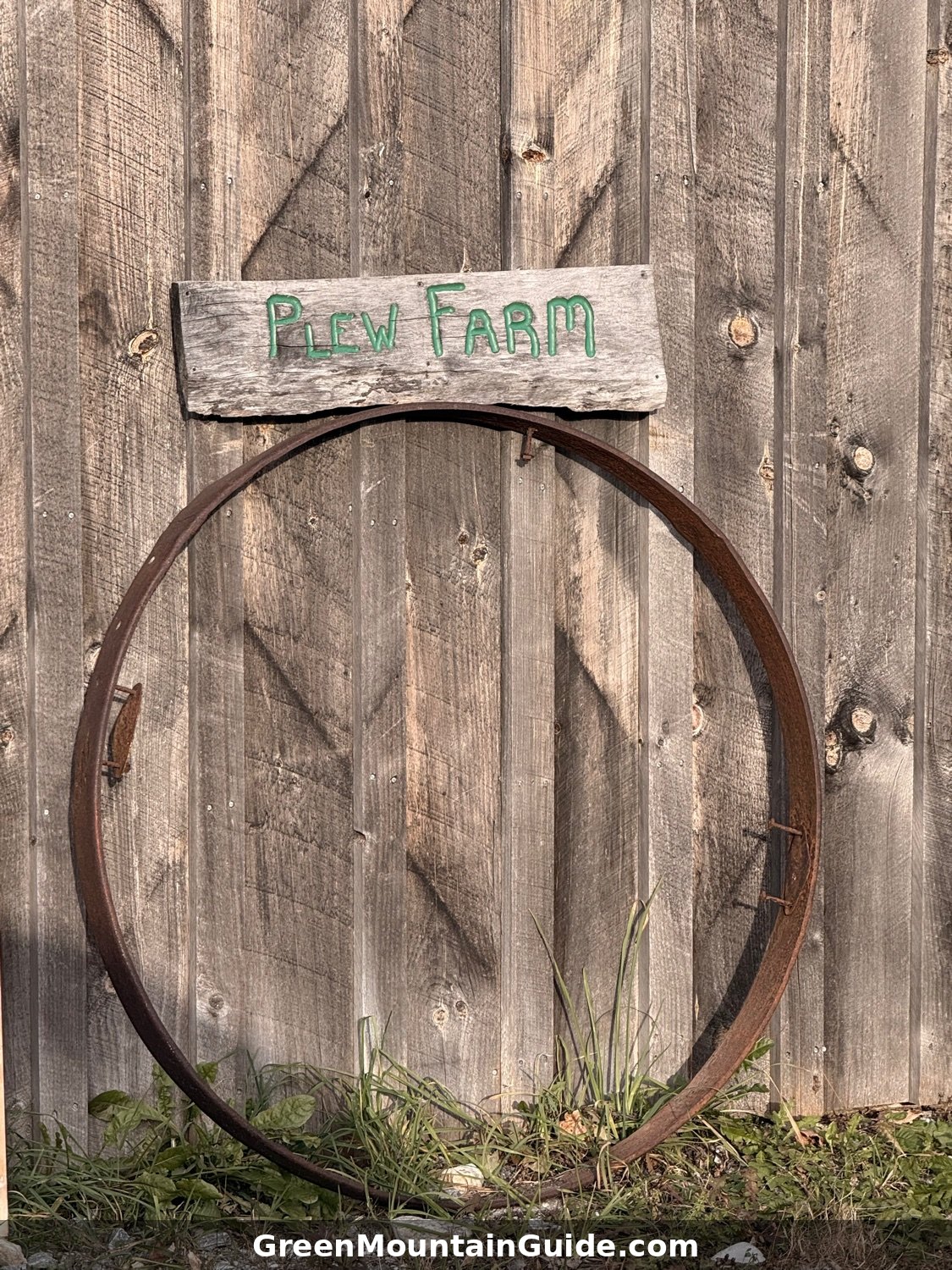 A hand-painted Plew Farm sign and an old wagon wheel rim on the barn wall